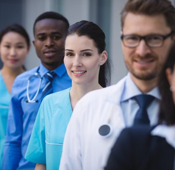 Portrait of smiling doctors standing in row at hospital premises